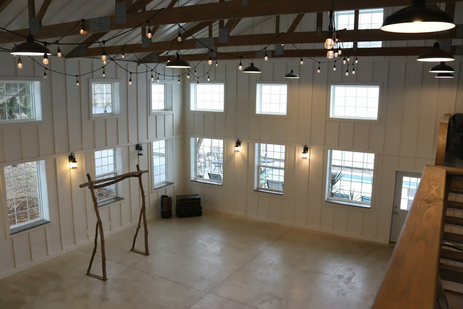 An empty barn venue with string lights and a wooden ceremony arch