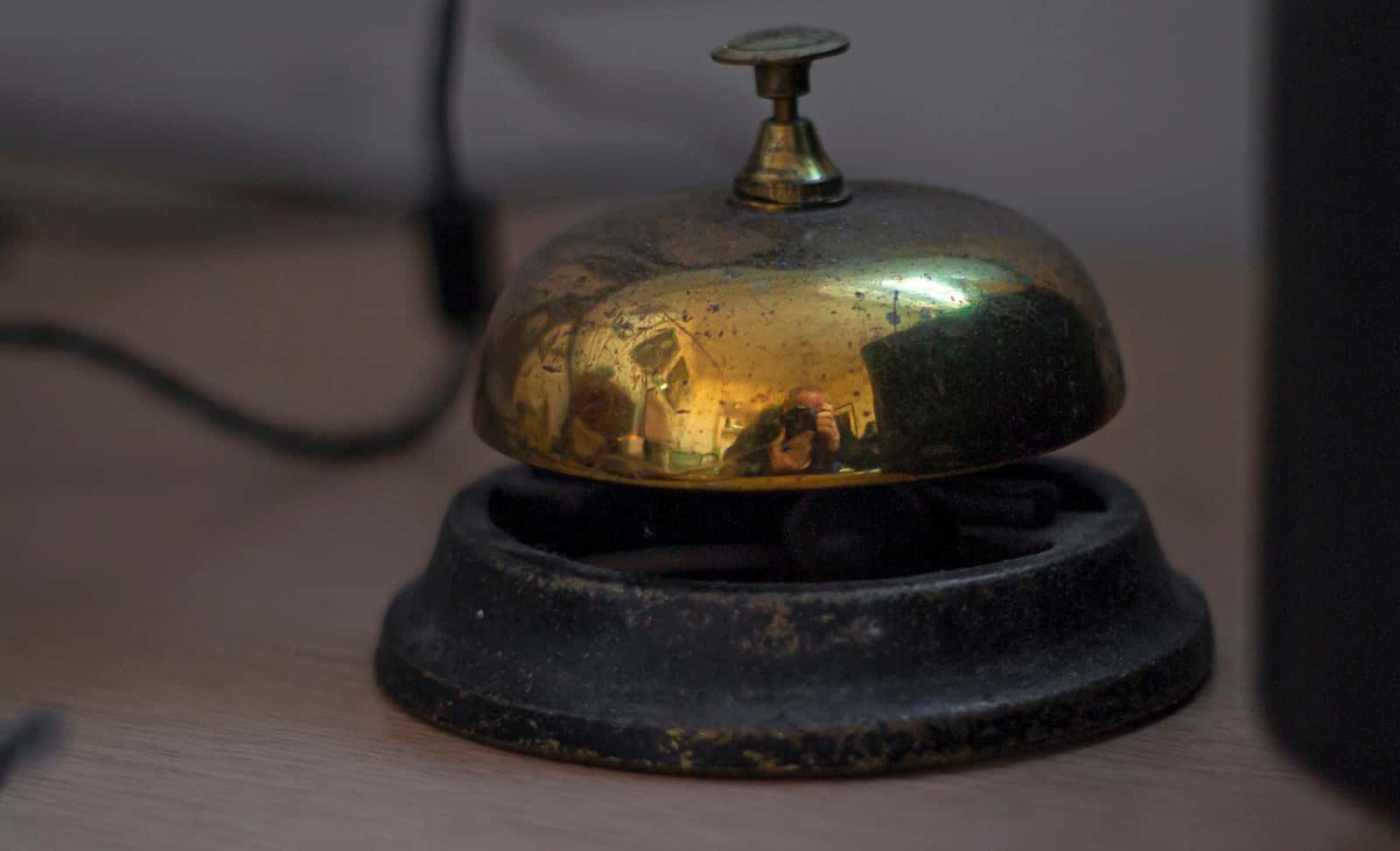 A brass service bell on a wooden reception desk
