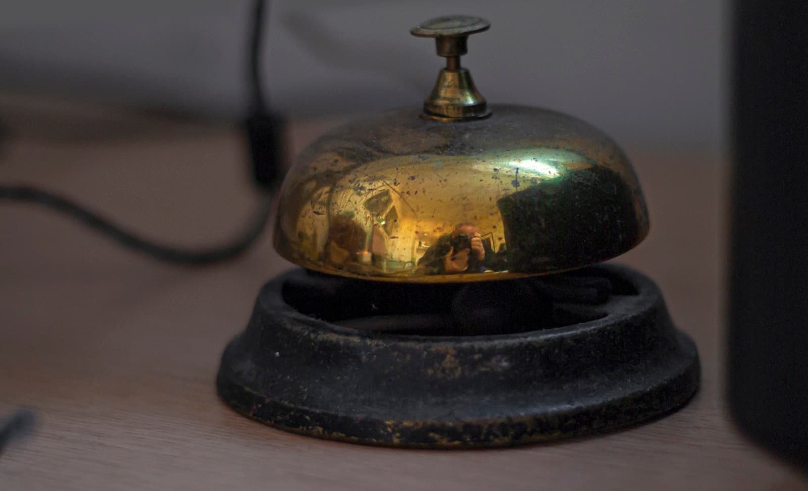 A brass service bell on a wooden reception desk