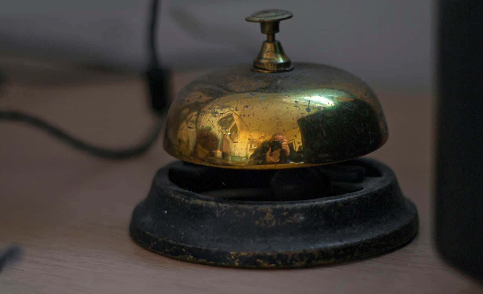 A brass service bell on a hotel reception desk